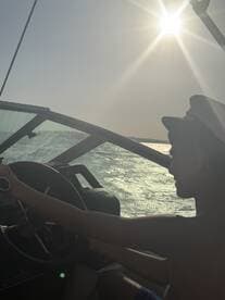 A young boy steers a boat under the bright sun, capturing the essence of adventure on the water.