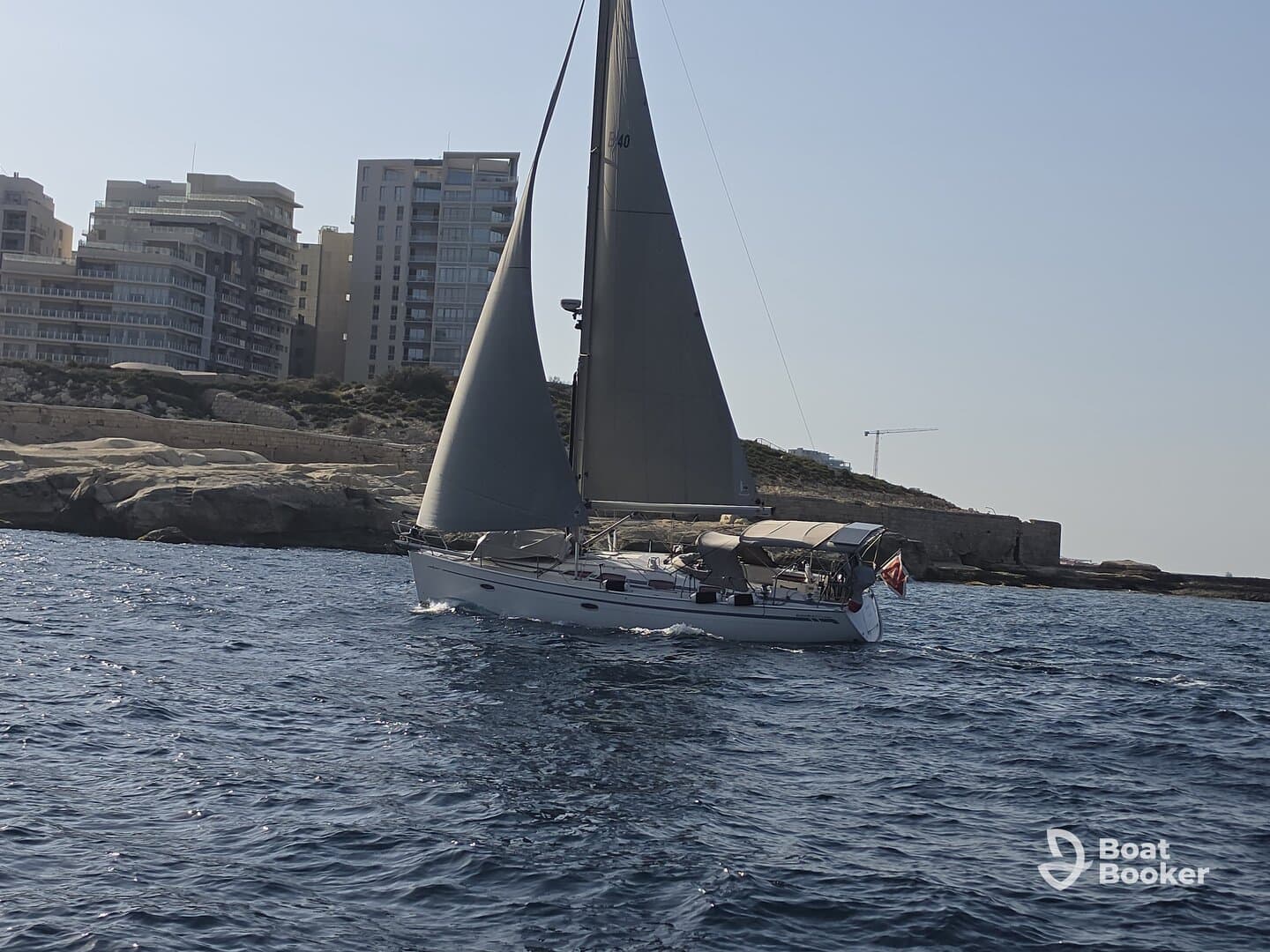 A sleek sailboat navigates the waters near a coastal city, showcasing the perfect blend of adventure and urban scenery.
