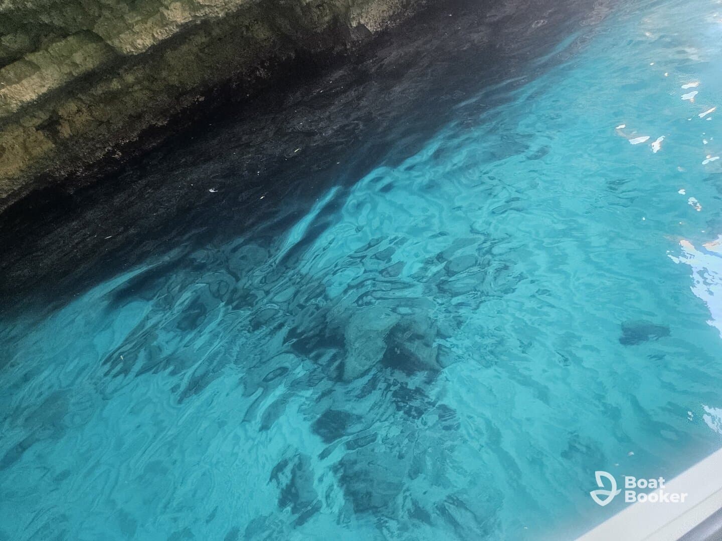 An unclear image of water with rocky formations beneath, lacking identifiable features or subjects.
