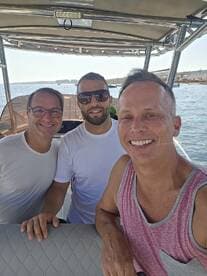 A cheerful group of friends poses for a selfie aboard a boat, capturing the joy of their day on the water.
