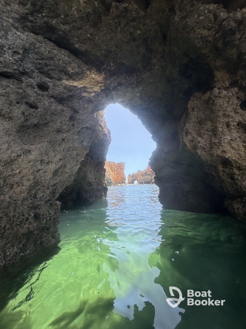 A stunning view through a natural rock arch, revealing the tranquil waters and rugged coastline beyond — a perfect representation of coastal exploration.