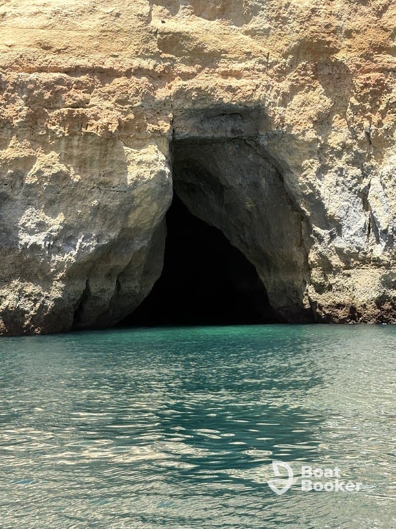A stunning view of a coastal cave entrance surrounded by clear turquoise waters, perfect for exploring hidden gems during a boating adventure.