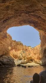 A stunning view from inside a cave, showcasing the vibrant rock formations and tranquil waters — a perfect spot for exploration and adventure on the coast.