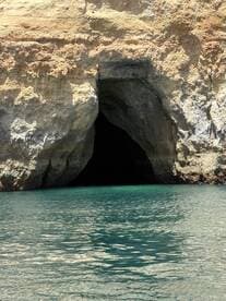 A stunning view of a coastal cave entrance surrounded by clear turquoise waters, perfect for exploring hidden gems during a boating adventure.