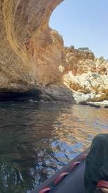 A scenic view of a cave entrance while kayaking, showcasing the stunning rock formations and tranquil waters — perfect for adventure seekers exploring coastal landscapes.