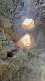 An abstract view of rock formations with light filtering through openings, creating an intriguing natural pattern.