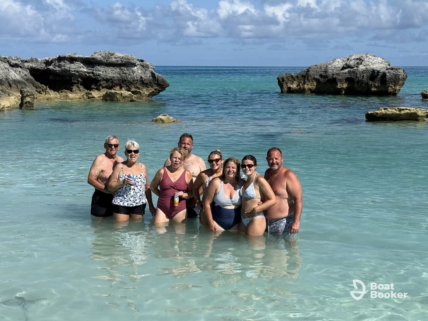 A joyful group of friends enjoys a sunny day at the beach, wading in the clear waters and celebrating together — perfect for memorable vacation moments.
