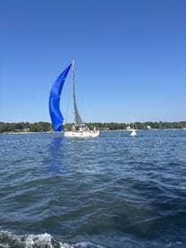 A vibrant sailboat with a striking blue sail glides through the water, showcasing the beauty of sailing on a clear day. Perfect for adventure seekers and sailing enthusiasts.
