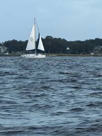 A serene view of a sailboat gracefully navigating through calm waters, showcasing the beauty of sailing and the tranquility of the surrounding landscape.