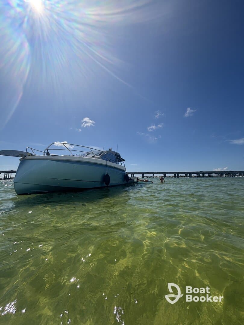 A boat anchored in shallow waters with people swimming nearby, capturing the essence of a fun day on the water.