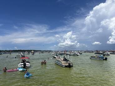 A vibrant scene of people enjoying a sunny day on the water, surrounded by various boats and activities — perfect for summer fun and social gatherings.