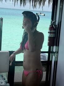 A girl enjoys a snack while snorkeling, showcasing a fun beach day with vibrant turquoise waters in the background.