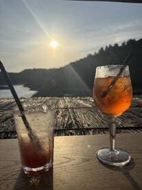 Two refreshing cocktails sit on a table, perfectly positioned to enjoy the sunset view — ideal for relaxing moments on a boat or at a seaside bar.