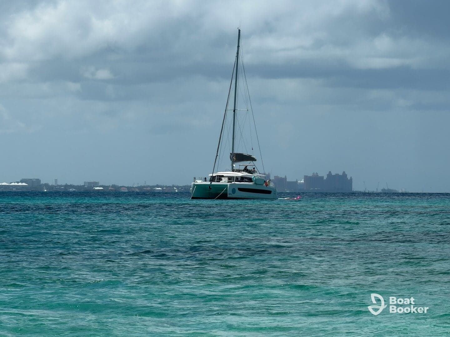 A serene view of a catamaran sailing in crystal-clear waters, set against a backdrop of distant resorts — perfect for showcasing luxury boating experiences.