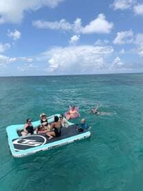 A lively group enjoys a day on a floating mat in the ocean, showcasing fun and relaxation under the sun.