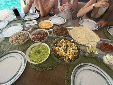 A vibrant spread of delicious taco ingredients and sides, perfect for a fun dining experience on the water. Guests enjoy a variety of fresh dishes while relaxing aboard.