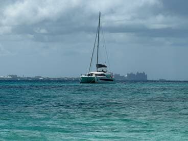 A serene view of a catamaran sailing in crystal-clear waters, set against a backdrop of distant resorts — perfect for showcasing luxury boating experiences.