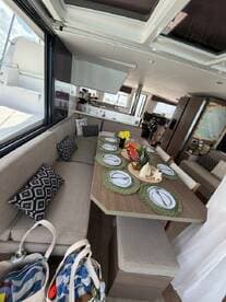 A beautifully arranged dining area inside a boat, featuring a cozy seating space and decorative table settings, perfect for enjoying meals on the water.