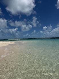 A sleek speedboat anchored on a pristine beach, surrounded by crystal-clear waters and a stunning blue sky — perfect for a day of relaxation and adventure.