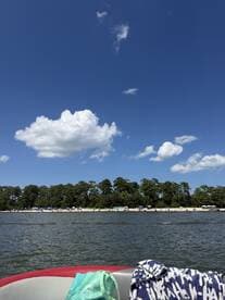 A scenic view from a boat showcasing a beautiful coastline with sandy beaches and vibrant clouds, perfect for a relaxing day on the water.