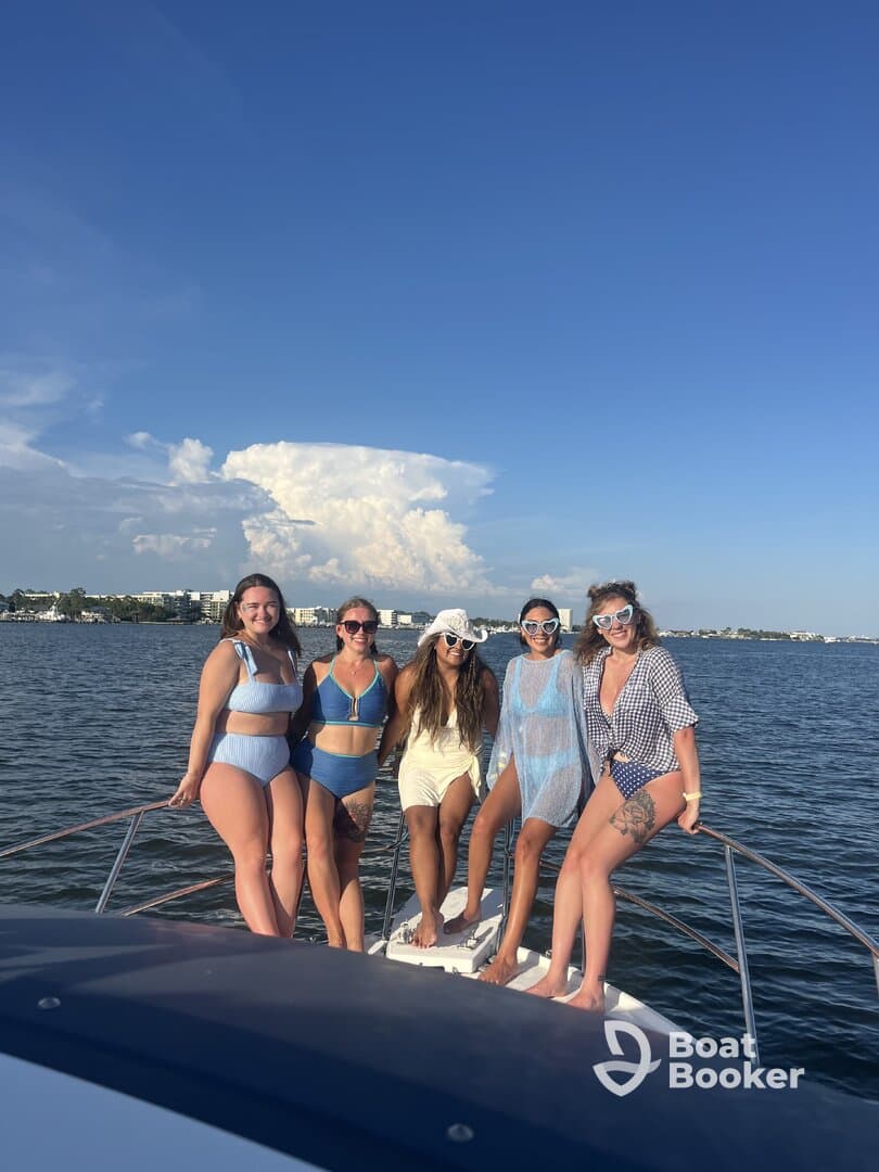 A fun group of friends poses on the bow of a boat, enjoying a sunny day on the water — perfect for summer celebrations and memorable outings.