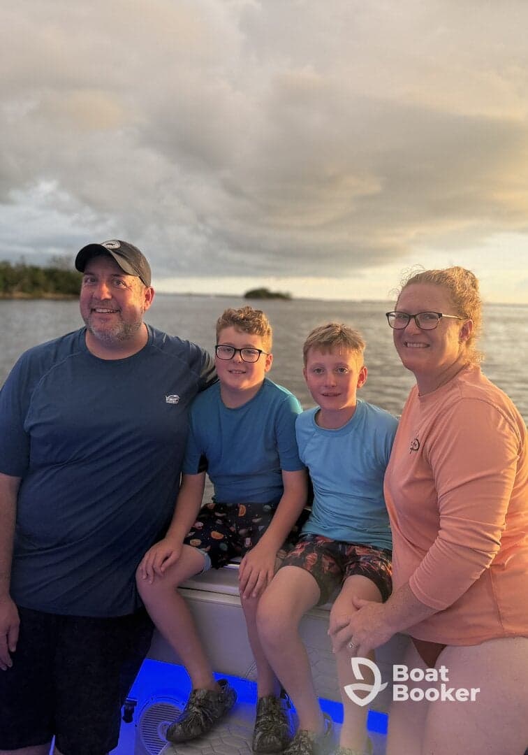 A joyful family poses together on a boat during sunset, capturing a memorable moment on the water — perfect for family outings and celebrations.