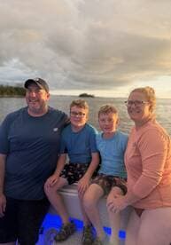A joyful family poses together on a boat during sunset, capturing a memorable moment on the water — perfect for family outings and celebrations.