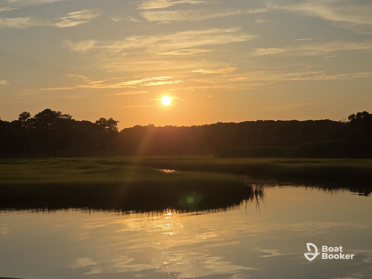 A stunning sunset casts a golden glow over tranquil waters, creating a picturesque scene perfect for evening boat trips or nature lovers.