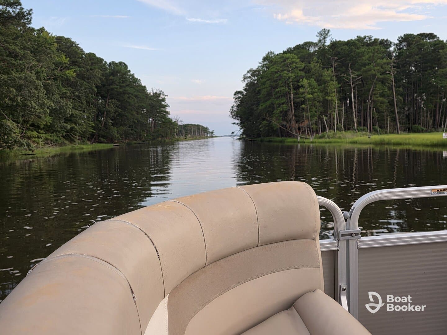 A cozy view from the seating area of a pontoon boat, showcasing a serene waterway surrounded by lush greenery — perfect for relaxing outings on the water.