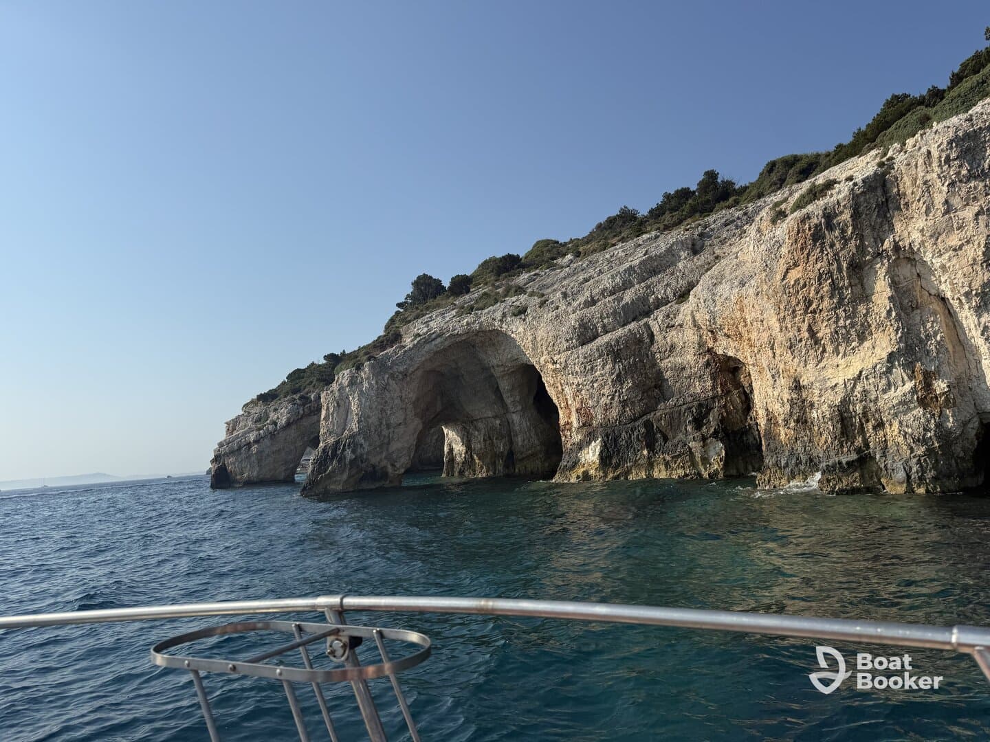 A stunning view of a rocky coastline with natural arches, captured from a boat, showcasing the beauty of the surrounding waters and landscape.