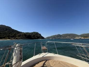 A scenic view from the bow of a boat, showcasing the lush green hills and clear waters, perfect for exploring coastal landscapes.