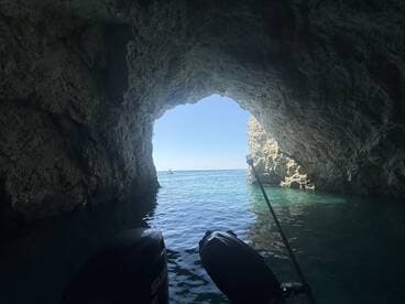 A stunning view from inside a cave looking out towards the ocean, showcasing the beautiful turquoise waters and rocky formations — perfect for adventure seekers exploring coastal landscapes.