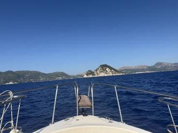 A stunning view from the bow of a boat cruising through deep blue waters, with picturesque islands in the background — perfect for exploring coastal destinations.