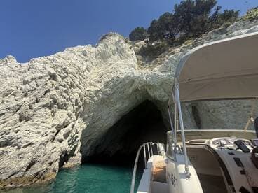 A scenic view of a boat approaching a stunning rocky cave along the coastline, showcasing the natural beauty of the area.