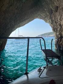 A stunning view from inside a cave, showcasing a sailboat anchored in the turquoise waters — a perfect representation of coastal adventures and scenic explorations.