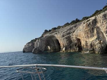 A stunning view of a rocky coastline with natural arches, captured from a boat, showcasing the beauty of the surrounding waters and landscape.