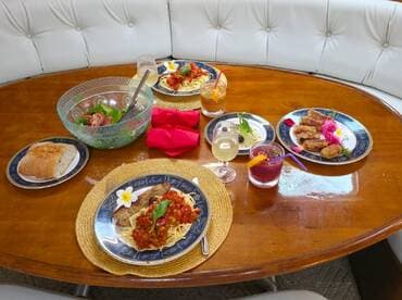 A beautifully arranged dining table on a boat featuring gourmet dishes and refreshing cocktails, perfect for an upscale dining experience on the water.