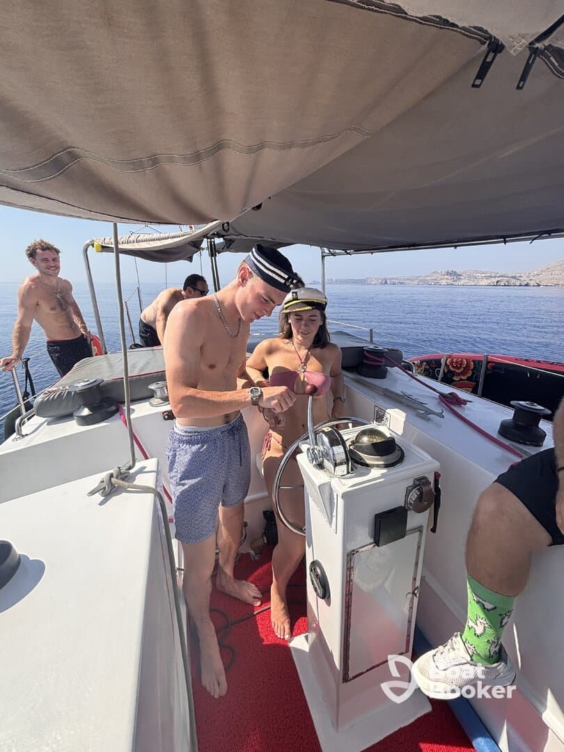 A lively group enjoys a sunny day on the boat, engaging at the helm and making the most of their nautical adventure.