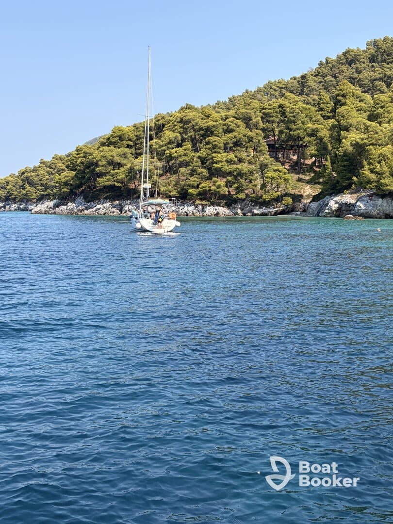A picturesque sailboat navigates through clear waters, surrounded by lush greenery — an ideal scene for sailing enthusiasts and nature lovers.
