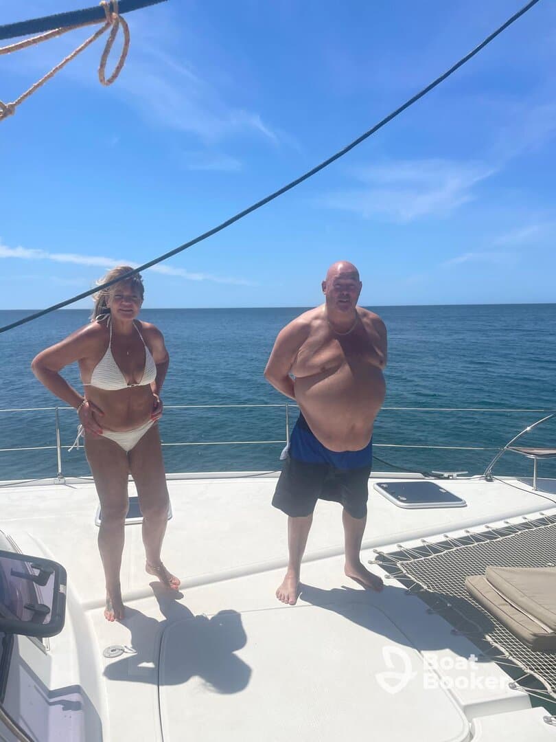 A couple enjoys a sunny day on the deck of a boat, with the ocean stretching out behind them — perfect for capturing memorable moments at sea.