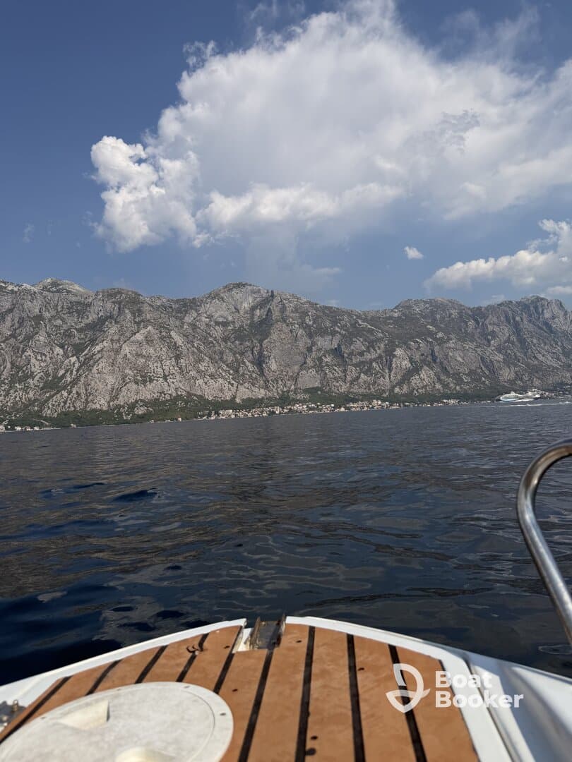 A scenic view from the bow of a boat, showcasing majestic mountains and clear waters, perfect for exploring coastal landscapes.