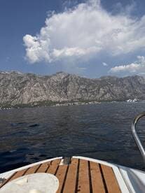 A scenic view from the bow of a boat, showcasing majestic mountains and clear waters, perfect for exploring coastal landscapes.