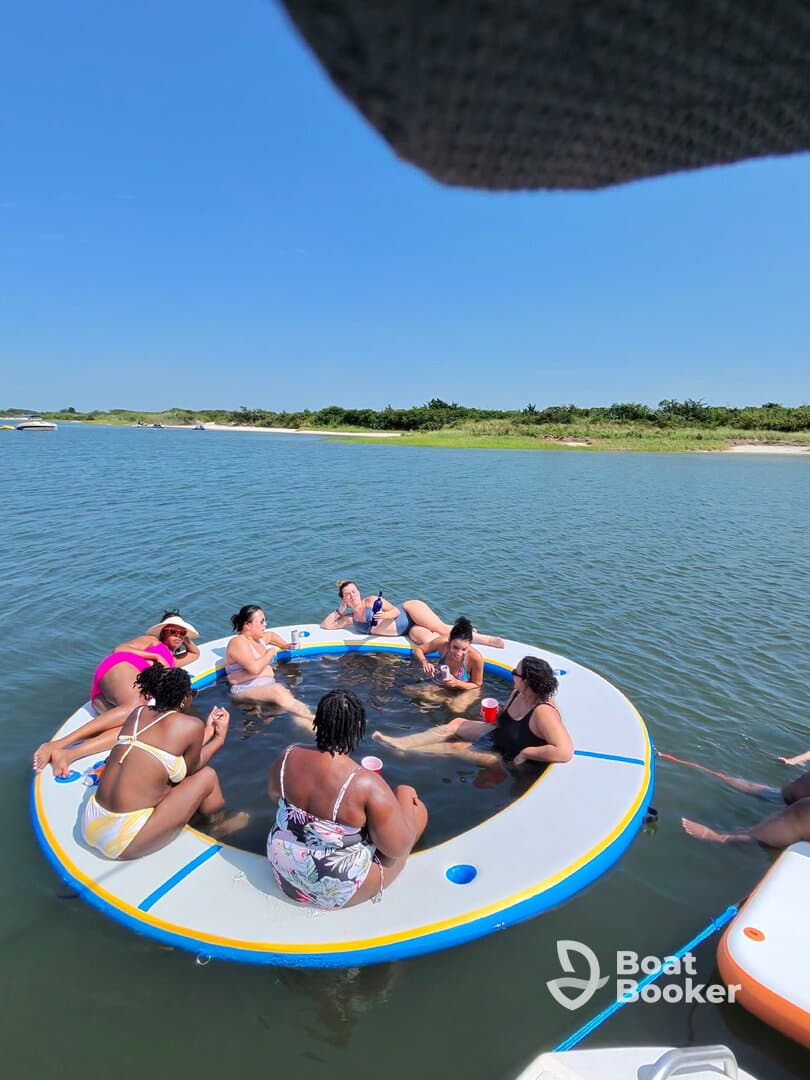 A lively group enjoys a fun day on a floating mat in the water, perfect for summer parties and relaxation with friends.