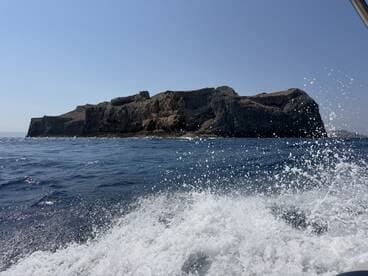 A stunning view of a rugged coastline from the water, showcasing the natural beauty of the island — perfect for adventure seekers and nature lovers.