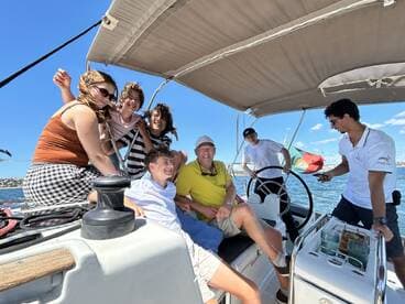 A joyful group enjoys a sailing experience on a yacht, capturing moments of laughter and camaraderie under the sun.