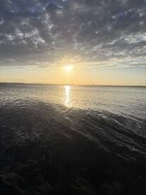 A stunning sunset over calm waters, with reflections creating a serene atmosphere — perfect for capturing the beauty of nature during a boating trip.