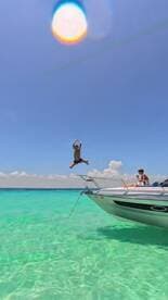 A child joyfully jumps off the bow of a boat into the crystal-clear waters, capturing the essence of summer fun and adventure on the water.