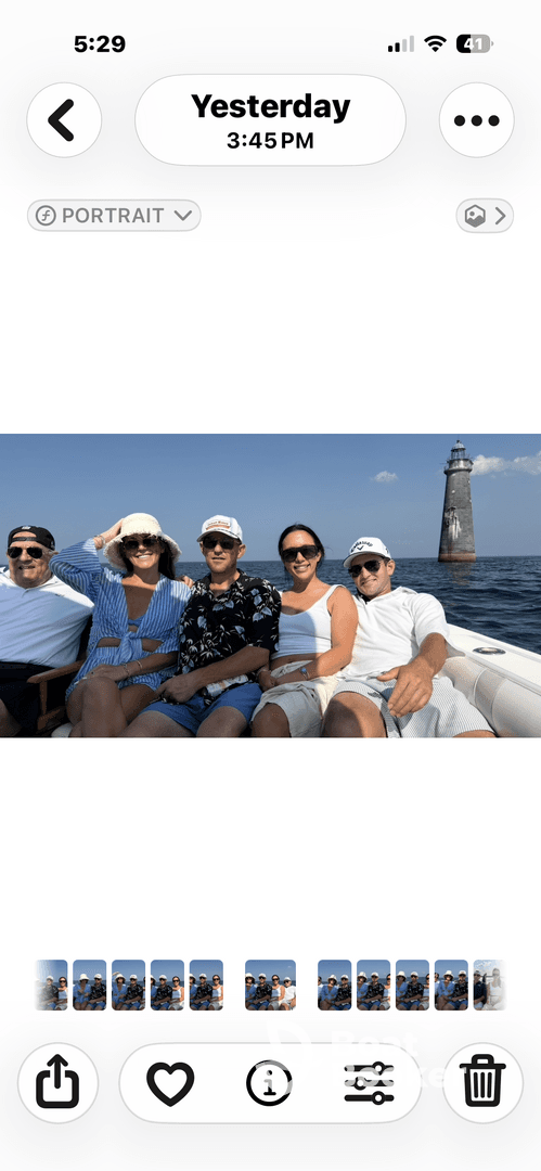 A cheerful group of friends enjoys a day on the water, posing for a photo with a lighthouse in the background — perfect for memorable boating adventures.