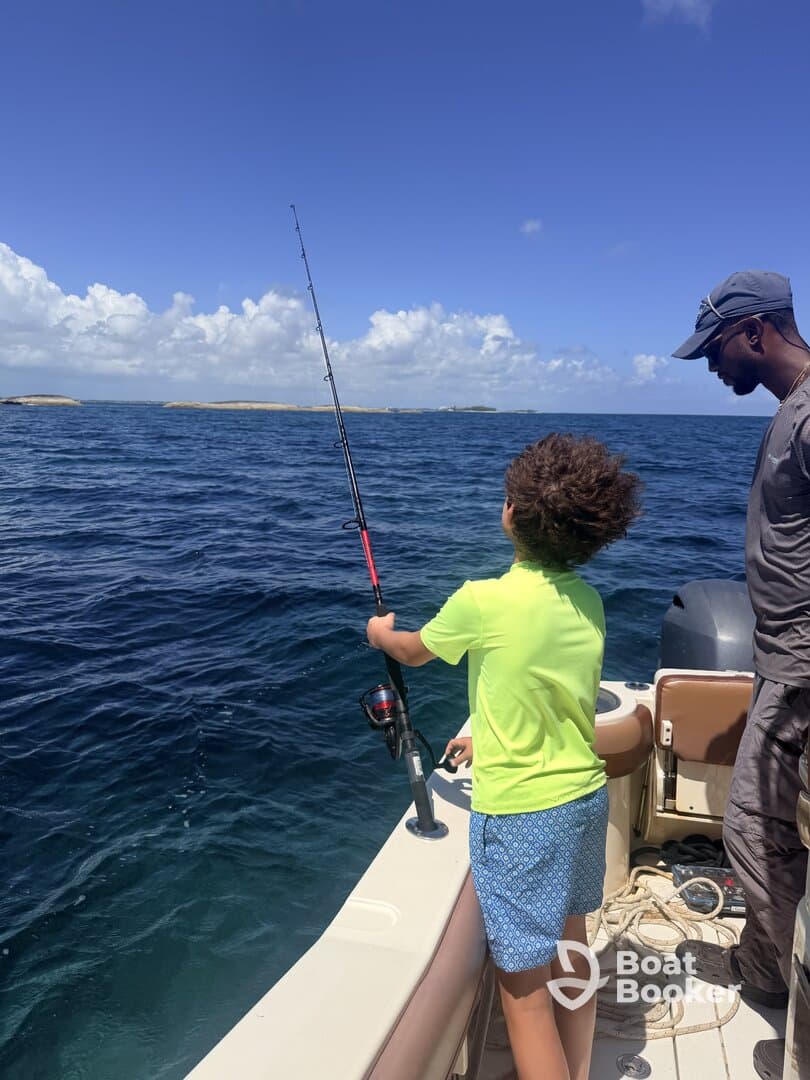 A child enjoys fishing on a boat, guided by an adult, surrounded by the beautiful ocean — a perfect family adventure on the water.