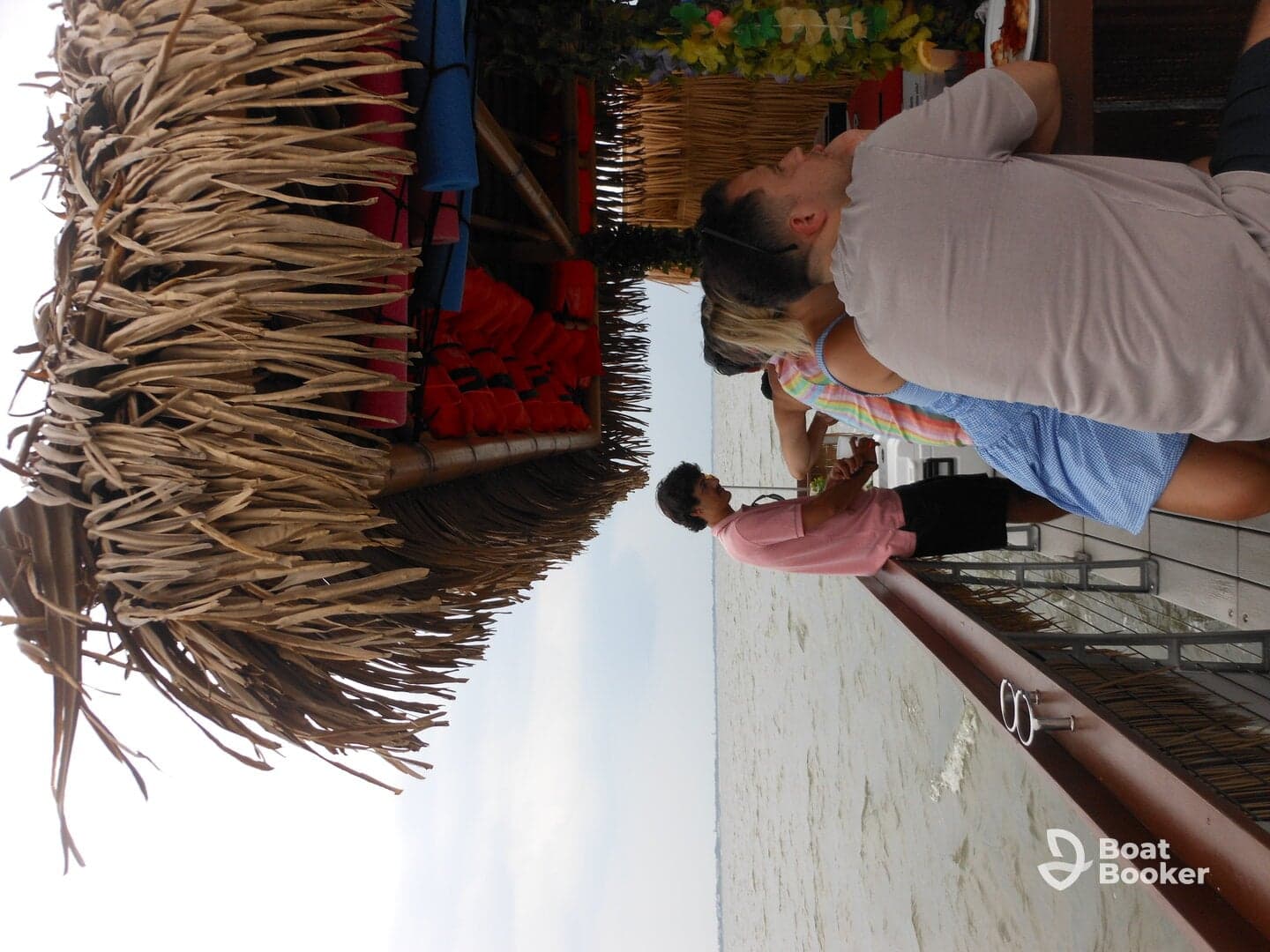 A lively group enjoys drinks and food at a waterfront dining area, perfect for socializing and relaxation on the water.